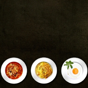 Drei Teller auf dunklem Hintergrund: links mit Tomatensuppe, in der Mitte mit Spaghetti, rechts mit Reis und einem Spiegelei.