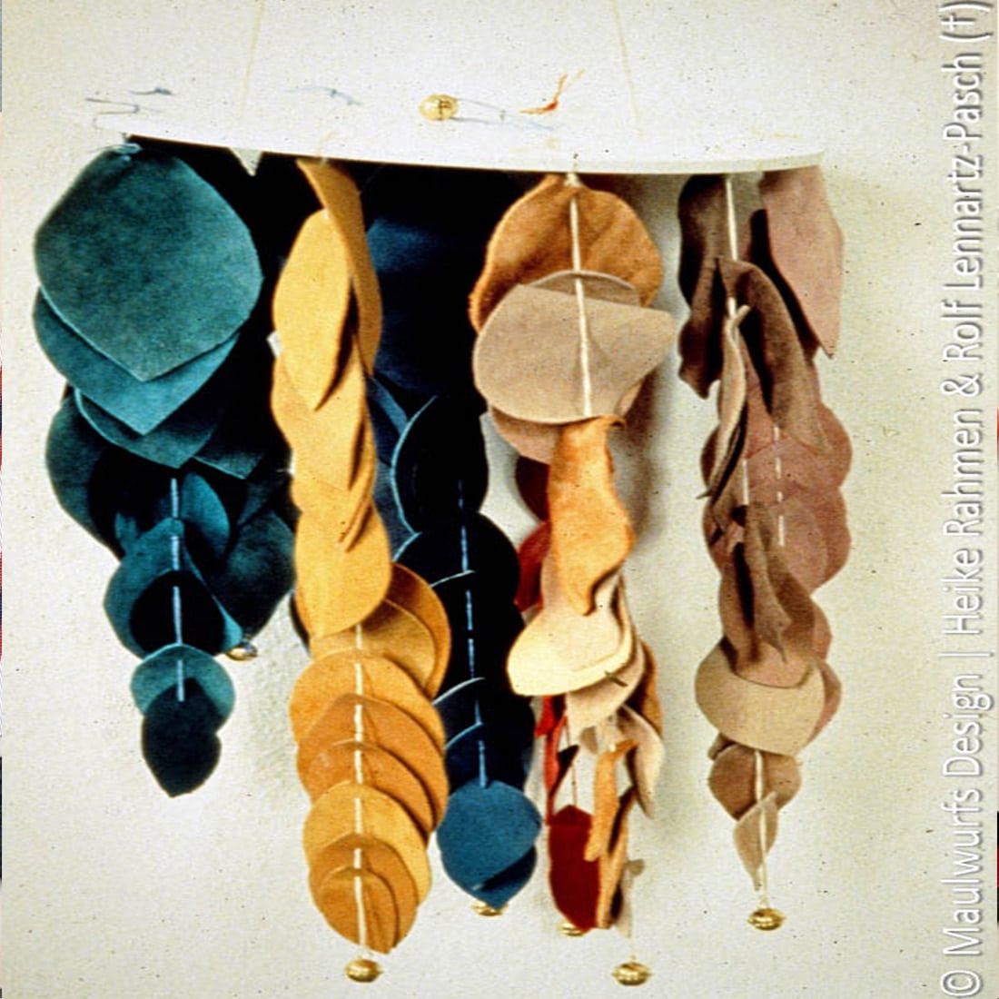 Verschiedene Lederblätter in unterschiedlichen Farben hängen als Teil einer künstlerischen Ausstellung an einer Wand.