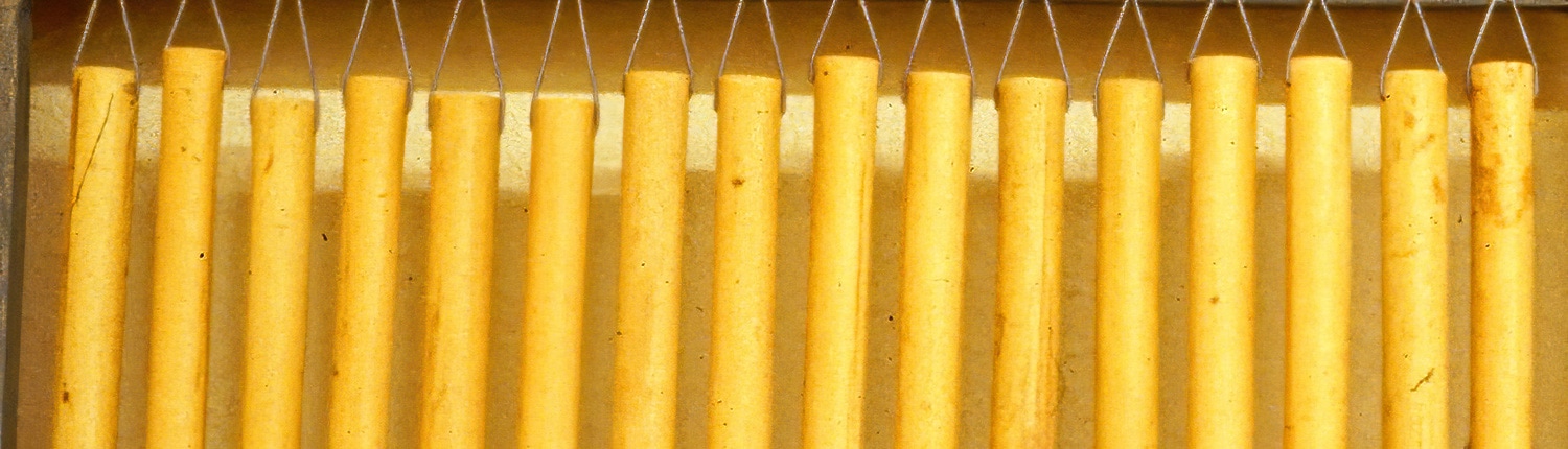 Nahaufnahme einer Reihe aufrecht stehender Brotstangen in goldbraunem Farbton vor einem gelben Hintergrund.