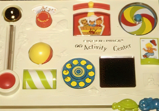 Aktivitätszentrum für Kinder mit farbenfrohen Sinnesspielzeugen, darunter ein roter und gelber Kreisel, Bälle und verschiedene strukturierte Platten.