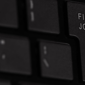 Nahaufnahme einer Tastatur mit einer hervorgehobenen Taste mit der Aufschrift „Job finden“, umgeben von anderen schwarzen Tasten.