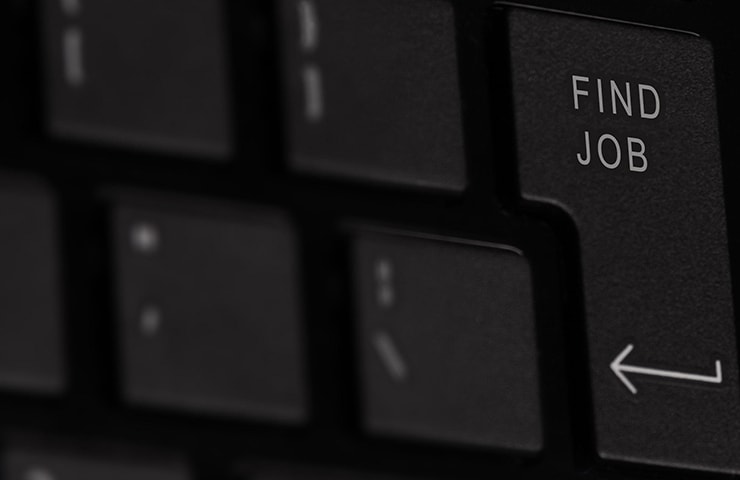 Nahaufnahme einer Tastatur mit einer hervorgehobenen Taste mit der Aufschrift „Job finden“, umgeben von anderen schwarzen Tasten.