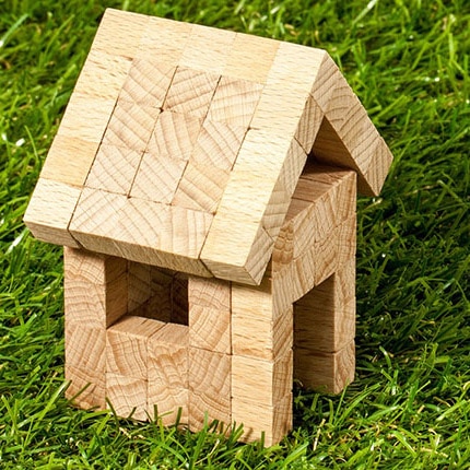 Ein kleines Holzblockhaus auf dem Gras, aus ineinander greifenden Teilen ohne sichtbare Nägel oder Klebstoff konstruiert.