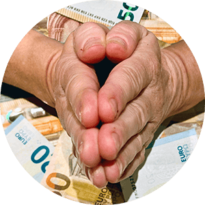 Zwei Hände, die in einer Gebetsgeste über einem Stapel Euro-Banknoten zusammengehalten werden. Die Hände zeigen Falten und Alterserscheinungen. Im Hintergrund sind die verschiedenen Nennwerte der Euro-Banknoten zu sehen.